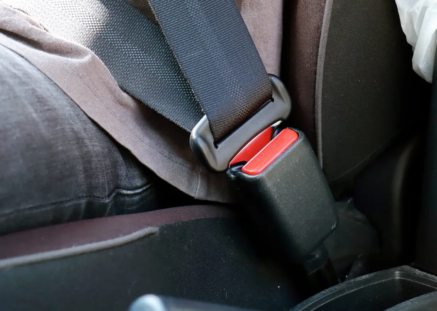 Rear seat position of a vehicle with the seat belt fastened into the buckle beside the seat cushion
