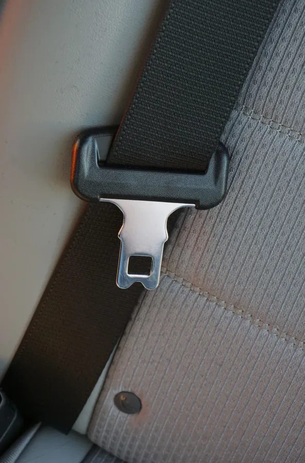 Metal seat belt tongue plate with rectangular locking slot held in a moulded webbing guide