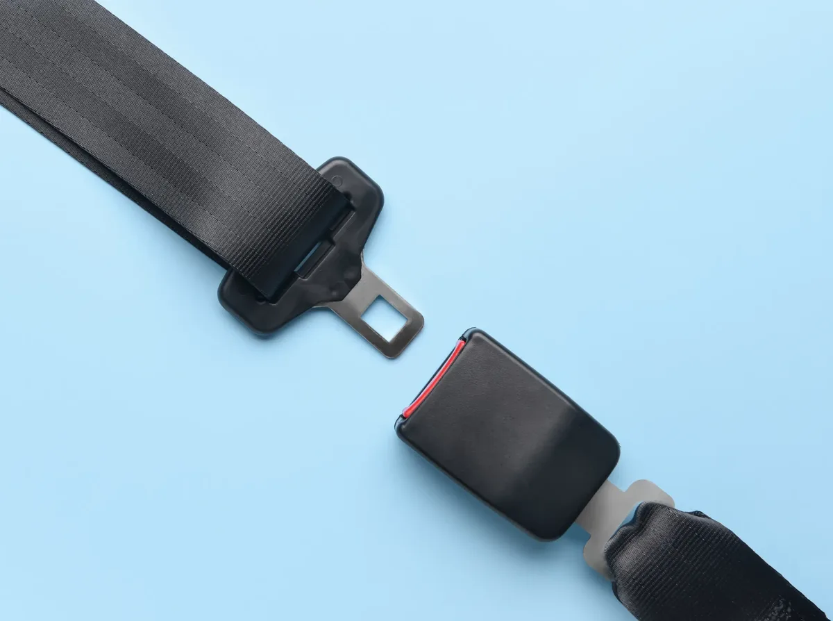 Seat belt tongue plate and buckle arranged apart on a plain surface showing both engaging faces